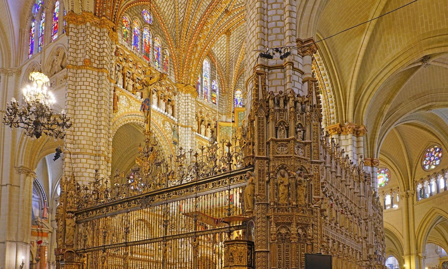 정교한 금색 조각상과 화려한 스테인드글라스가 돋보이는 고딕 양식 성당 내부의 웅장하고 성스러운 풍경입니다.