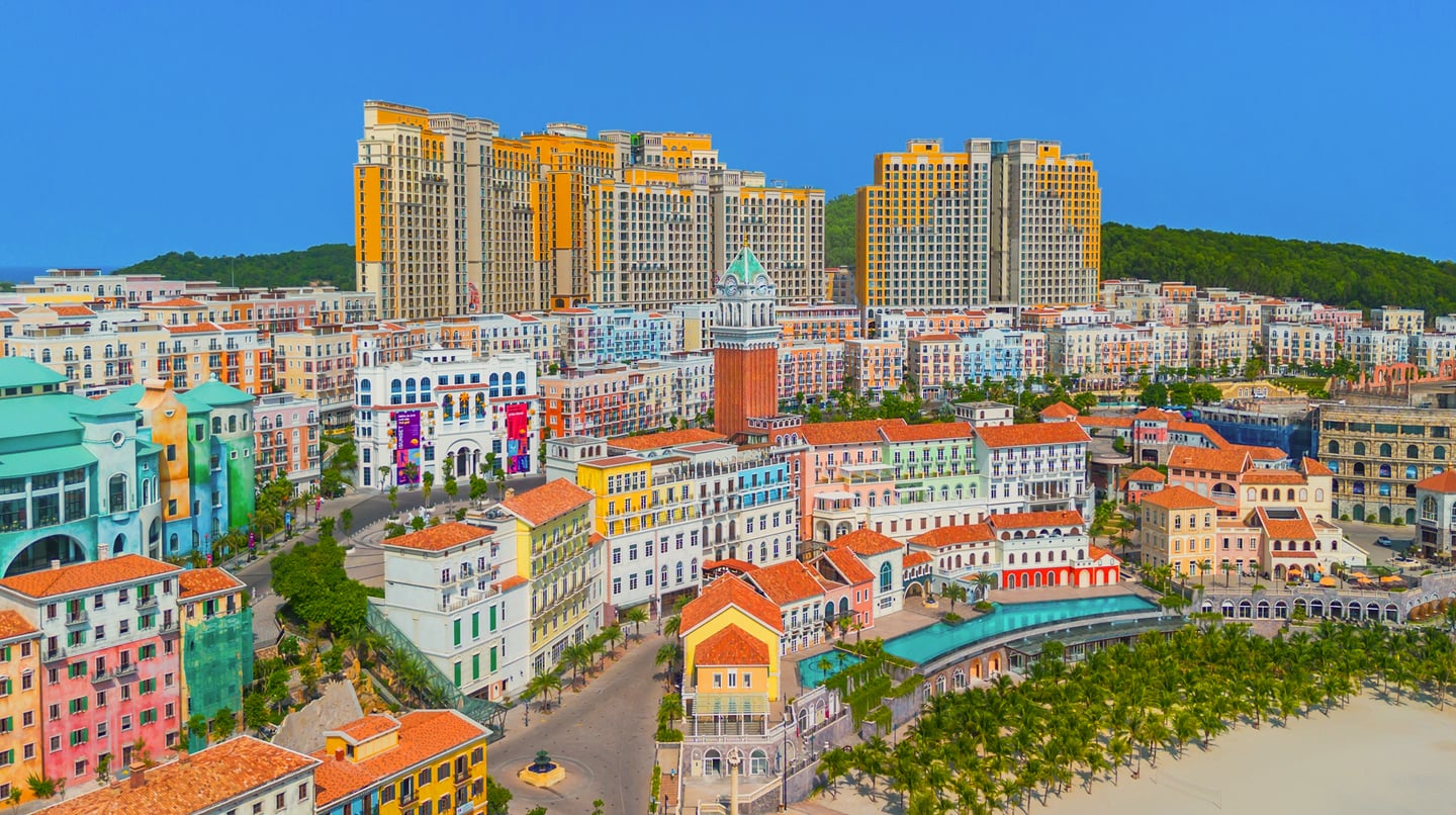 푸른 바다와 인접한 해안가에 위치한 화려한 색채의 유럽풍 건물들과 높은 시계탑이 돋보이는 베트남 푸꾸옥의 이국적인 리조트 단지 풍경입니다.