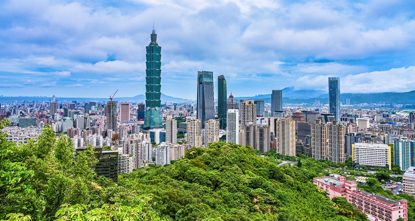 울창한 초록빛 산 뒤로 타이베이 101 타워와 현대적인 고층 빌딩들이 펼쳐진 대만 타이베이의 시원한 도시 파노라마 전경입니다.