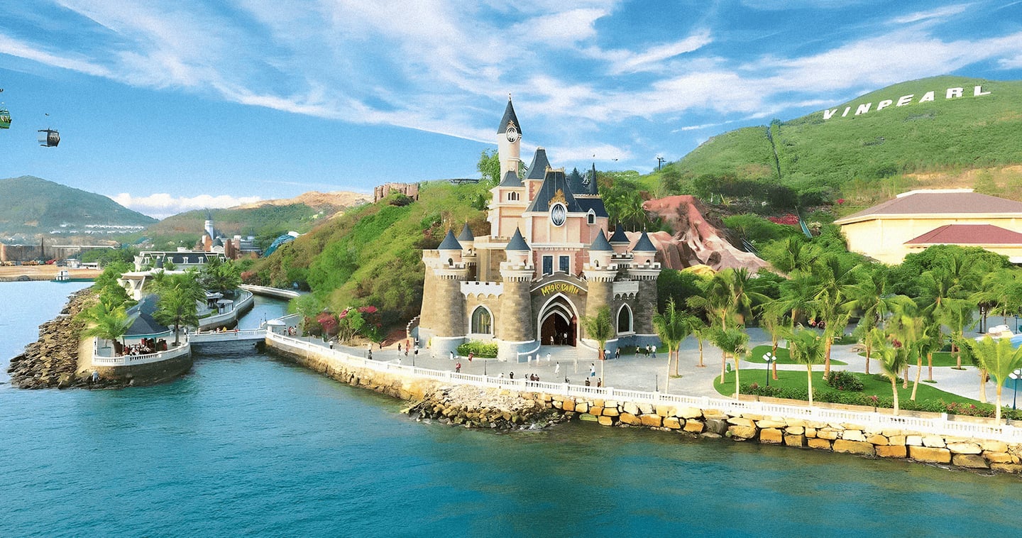 나트랑 빈원더스의 상징적인 매직 캐슬이 푸른 바다와 초록빛 언덕을 배경으로 서 있으며, 해안 산책로를 따라 사람들이 여유롭게 거니는 풍경입니다.