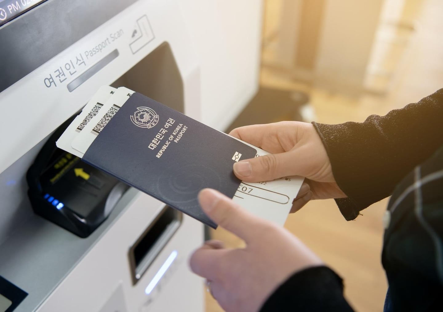 공항 셀프 체크인 기기 앞에서 대한민국 여권과 탑승권을 들고 출국 절차를 밟고 있는 여행객의 손을 클로즈업한 사진입니다.