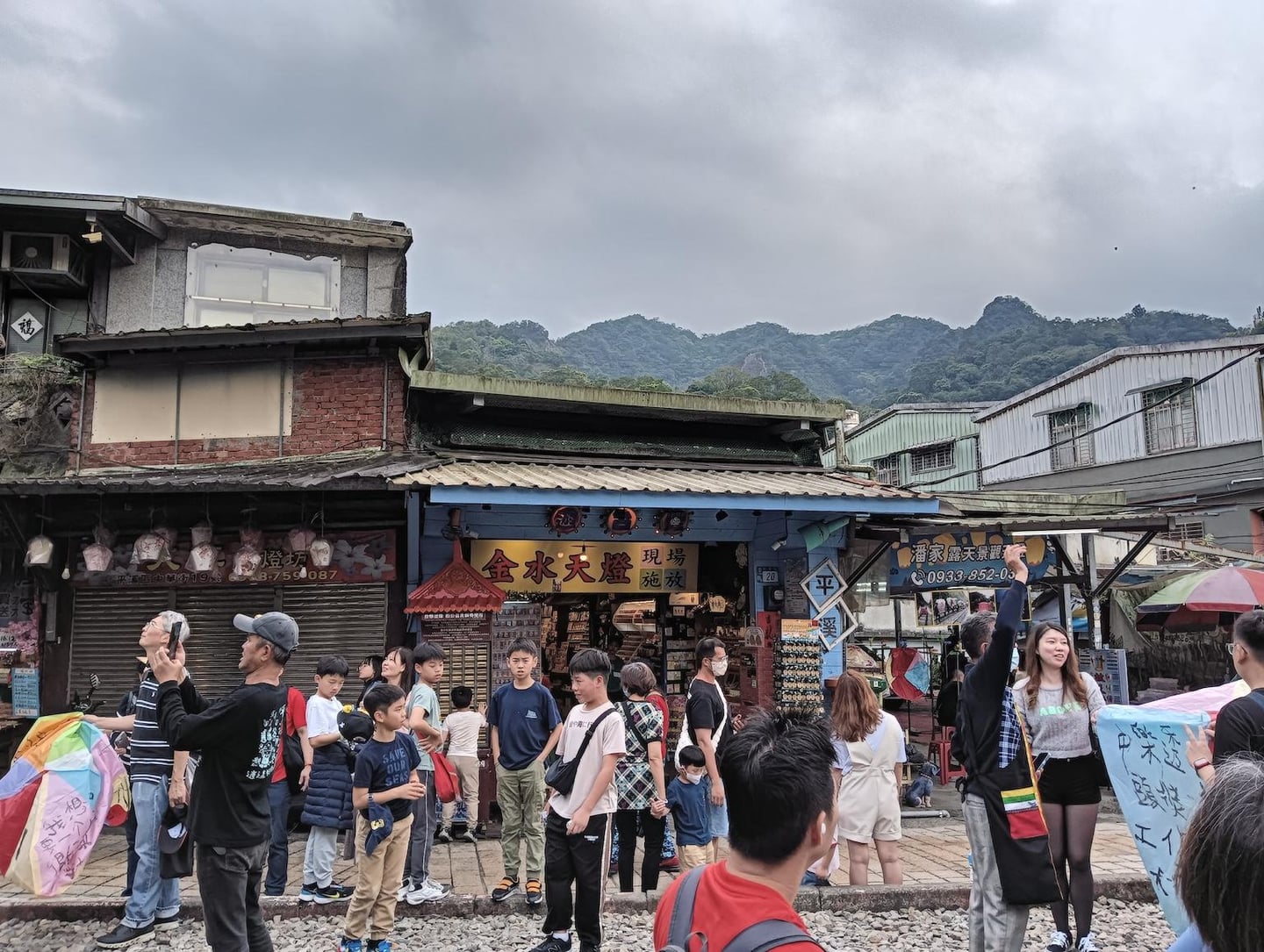 대만 스펀의 활기찬 거리에서 관광객들이 소원을 적은 천등을 들고 철길 주변에 모여 여행의 즐거움을 만끽하는 풍경입니다.