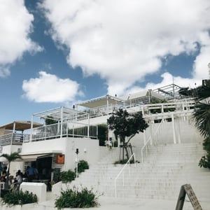 맑고 푸른 하늘을 배경으로 하얀색 계단과 테라스 건물이 층층이 쌓여 있는 오키나와 우미카지 테라스의 평화로운 전경입니다.