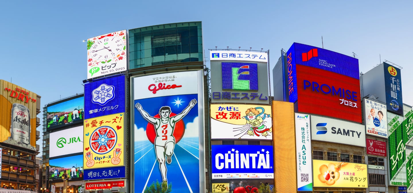 오사카 여행의 필수 코스인 도톤보리 거리에서 만나는 거대한 글리코상 광고판과 다채로운 색상의 상업용 네온사인들이 늘어선 화려한 도시 경관입니다.