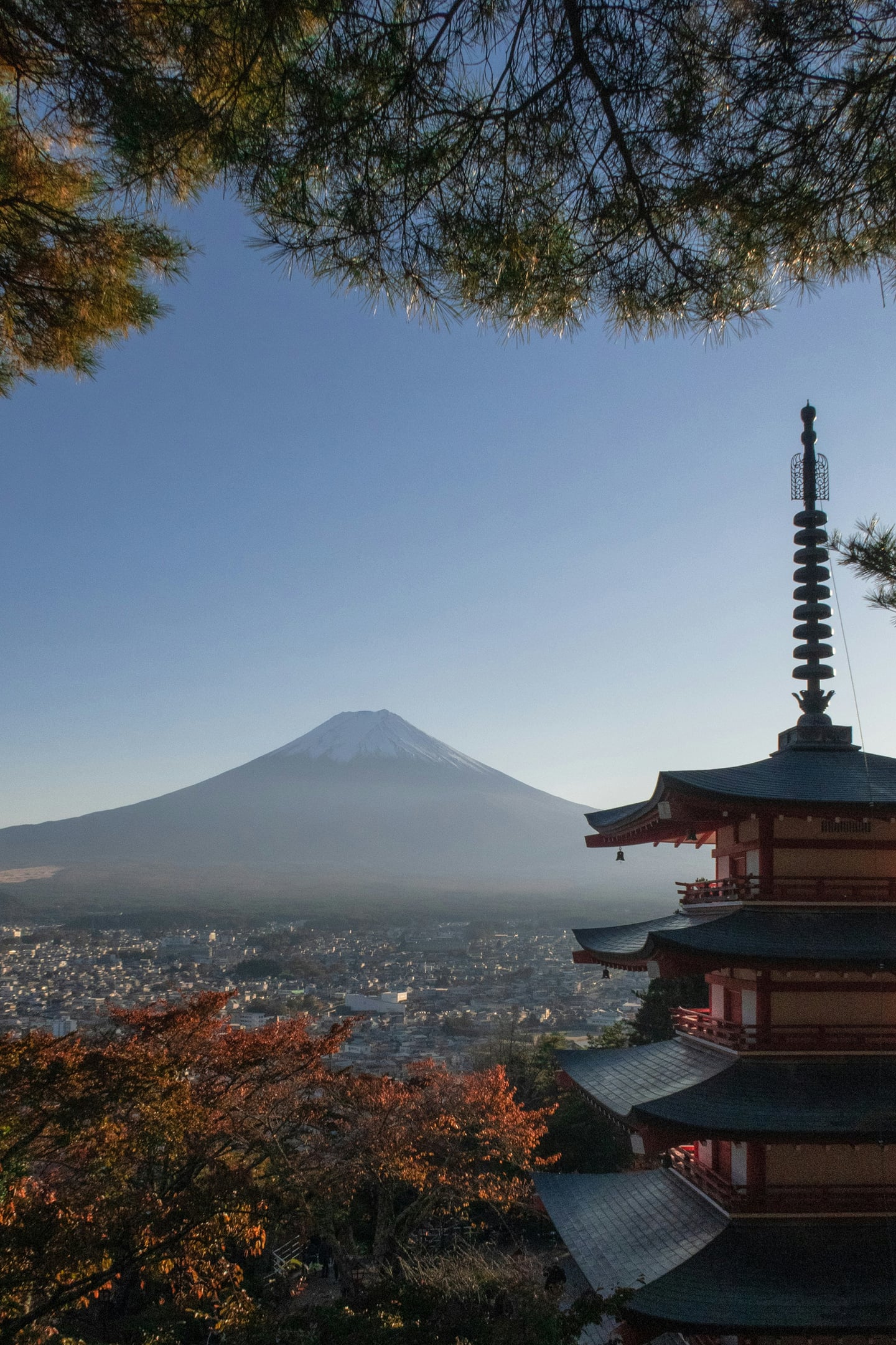 맑은 하늘을 배경으로 우뚝 솟은 후지산과 화려한 5층 목조 탑이 조화를 이루는 일본 야마나시현의 아름다운 가을 전경입니다.