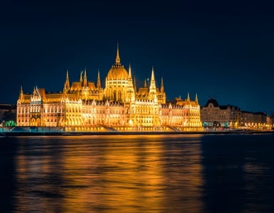 밤의 다뉴브 강변을 따라 황금빛 조명이 켜진 헝가리 국회의사당의 웅장한 모습과 강물에 비친 화려한 야경 반사광.