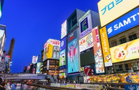 오사카 도톤보리 운하를 따라 늘어선 화려한 글리코상 네온사인과 대형 광고판들이 푸른 밤하늘 아래 빛나는 야경 모습입니다.