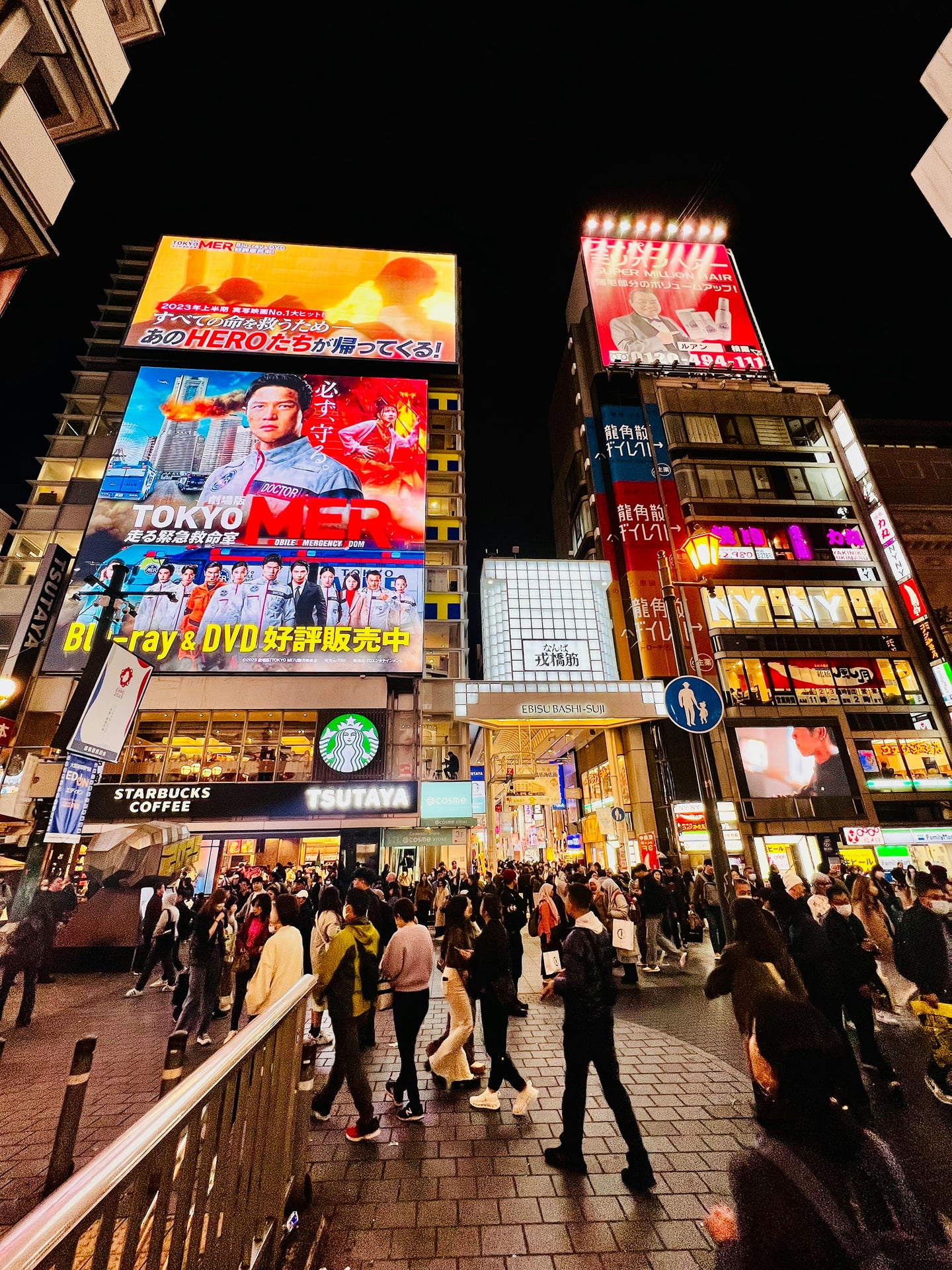 화려한 네온사인과 대형 광고판이 가득한 오사카 도톤보리 에비스바시 인근의 밤거리에서 수많은 관광객과 현지인들이 이동하는 활기찬 모습입니다.