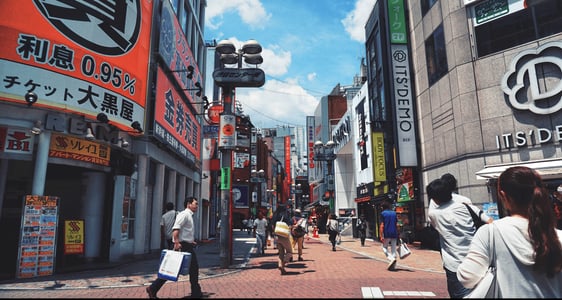 도쿄 시부야 센터가 거리의 화려한 일본어 간판들과 쇼핑을 즐기며 걷는 사람들의 활기찬 모습이 담긴 풍경입니다.