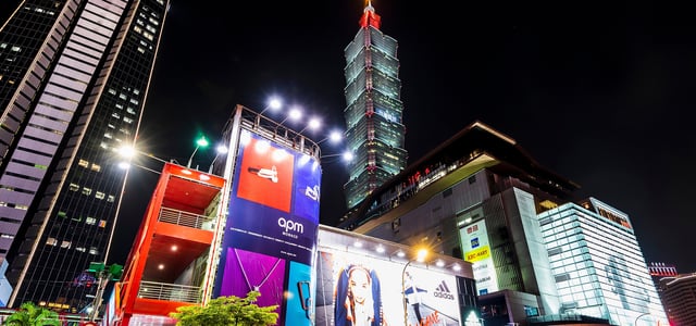 화려한 조명이 켜진 타이베이 101 빌딩과 대형 광고판이 가득한 번화가의 역동적인 밤 풍경을 담은 로우 앵글 사진입니다.