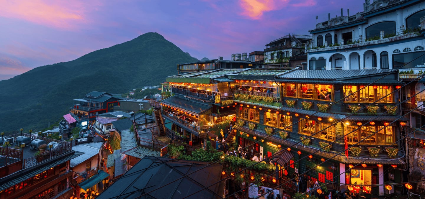 보랏빛 노을이 지는 하늘 아래 붉은 홍등이 가득 켜진 대만 지우펀의 고풍스러운 목조 건물들과 산등성이가 어우러진 야경입니다.