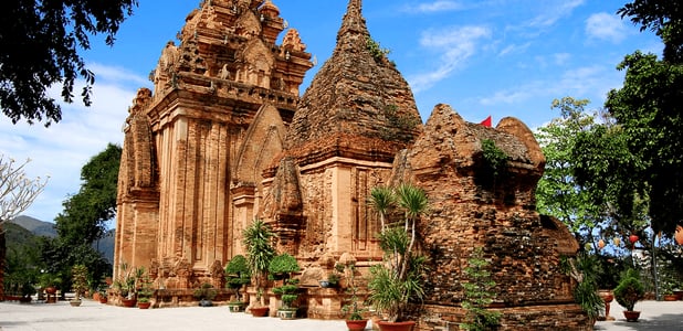 맑은 날씨 속에서 고풍스러운 붉은 벽돌 구조와 뾰족한 지붕이 인상적인 베트남 나트랑 포나가르 사원의 웅장한 건축물 외관 모습입니다.