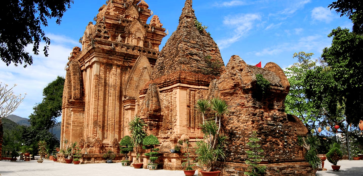 맑은 날씨 속에서 고풍스러운 붉은 벽돌 구조와 뾰족한 지붕이 인상적인 베트남 나트랑 포나가르 사원의 웅장한 건축물 외관 모습입니다.