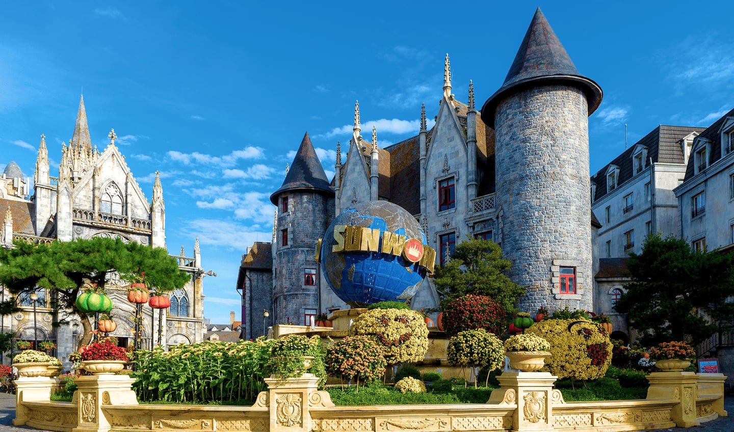 다낭 바나힐의 썬월드 지구본 조형물을 중심으로 고풍스러운 유럽식 성과 알록달록한 꽃들이 어우러진 테마파크의 전경입니다.