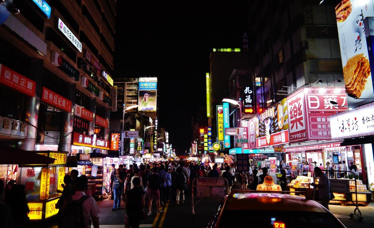 화려한 네온사인 간판이 가득한 대만의 밤거리 야시장에서 수많은 사람들이 노점상을 구경하며 걷고 있는 활기찬 풍경입니다.