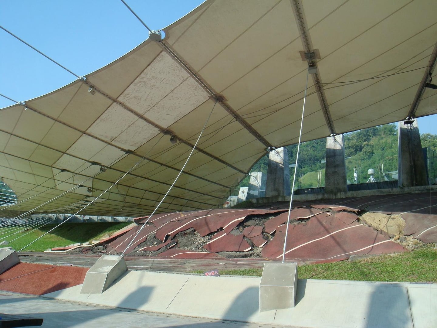 대만 921 지진 교육 원구에서 보존 중인 지진 피해로 솟아오르고 균열이 생긴 붉은색 육상 트랙과 이를 덮고 있는 거대한 흰색 차양막 구조물