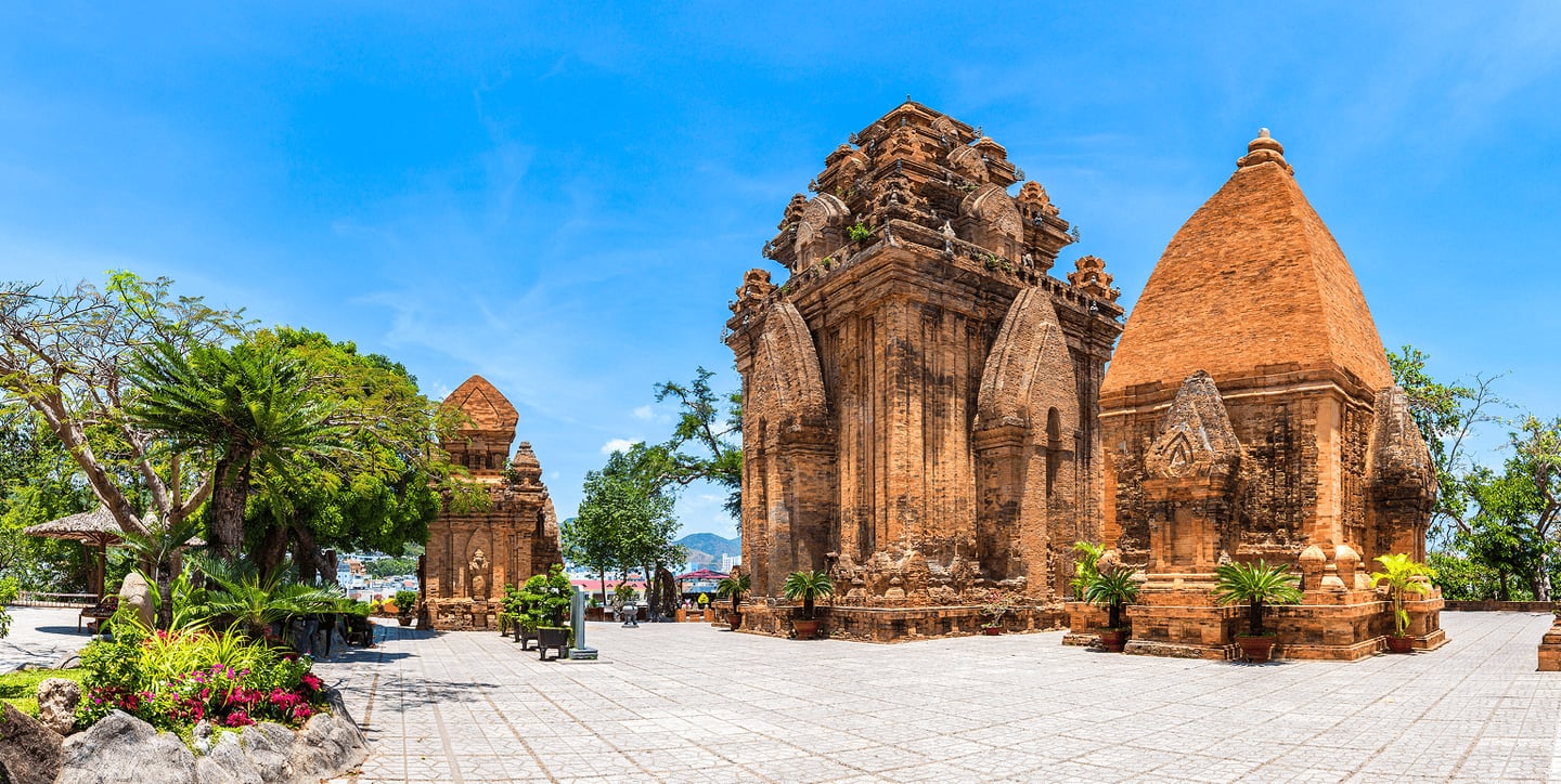 베트남 나트랑의 유서 깊은 포나가르 첨탑 사원 단지가 맑은 날씨 속에서 붉은 벽돌의 질감과 정교한 조각을 뽐내며 서 있는 풍경입니다.
