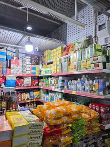 베트남 현지 상점 선반에 가득 진열된 알록달록한 커피 상자와 차 패키지 그리고 노란색 봉지에 담긴 간식들의 모습입니다.