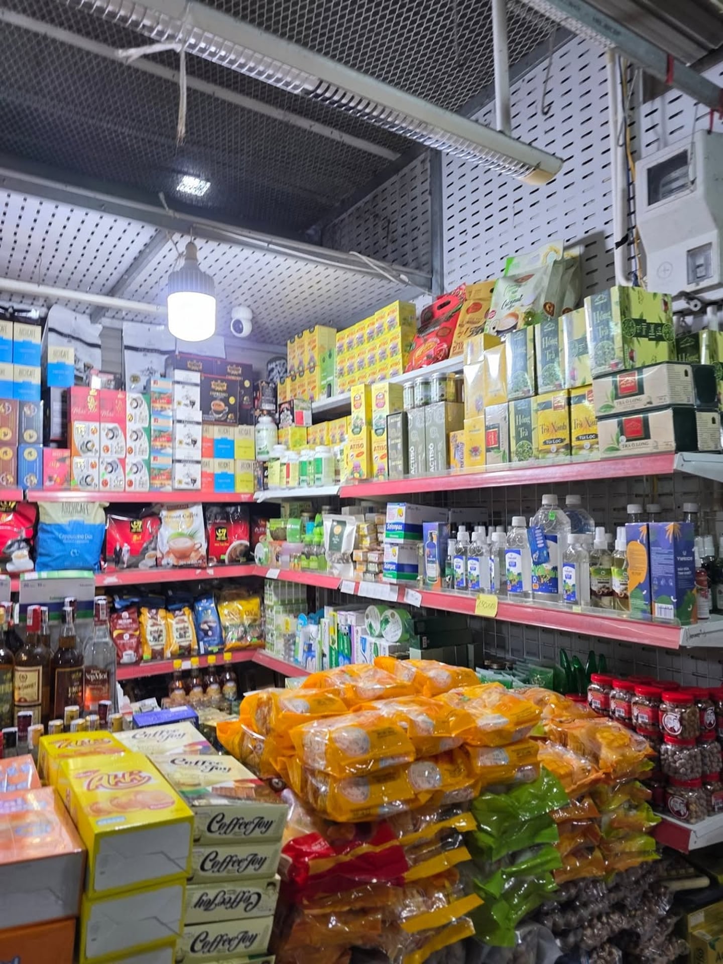 베트남 현지 상점 선반에 가득 진열된 알록달록한 커피 상자와 차 패키지 그리고 노란색 봉지에 담긴 간식들의 모습입니다.