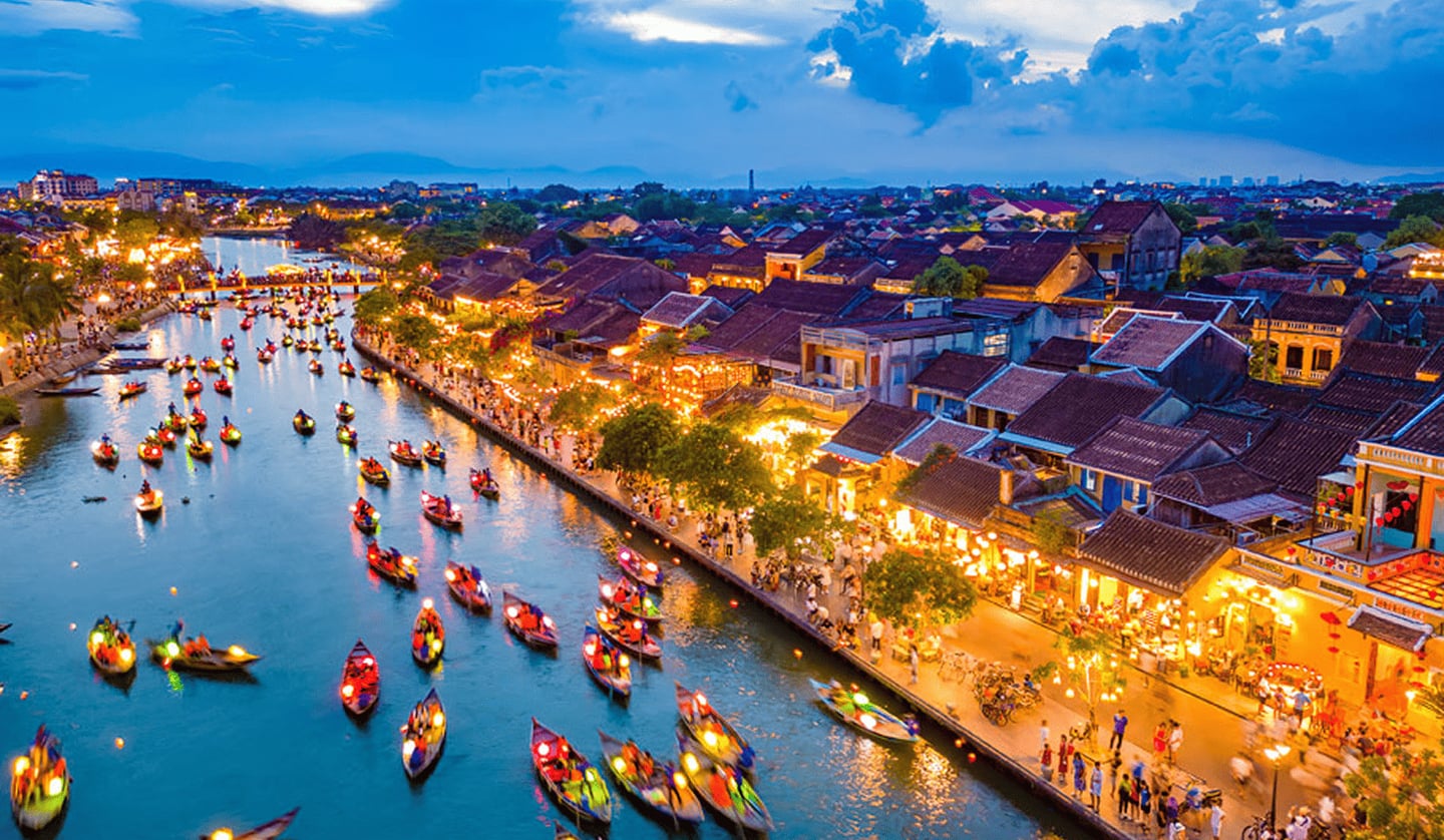 황혼이 내린 호이안 올드타운의 투본강을 따라 화려한 등불을 켠 배들이 줄지어 떠 있고 강변 산책로에는 활기찬 인파가 가득합니다.