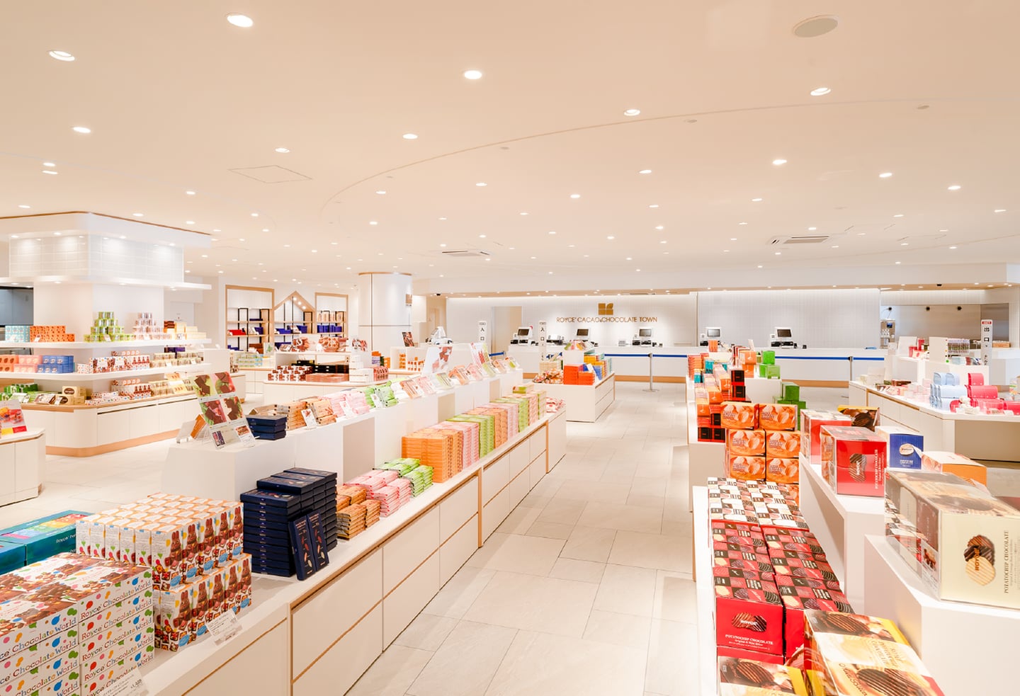 환한 조명 아래 다채로운 패키지의 초콜릿 상품들이 정갈하게 진열된 로이즈 초콜릿 타운의 넓고 깨끗한 매장 전경입니다.