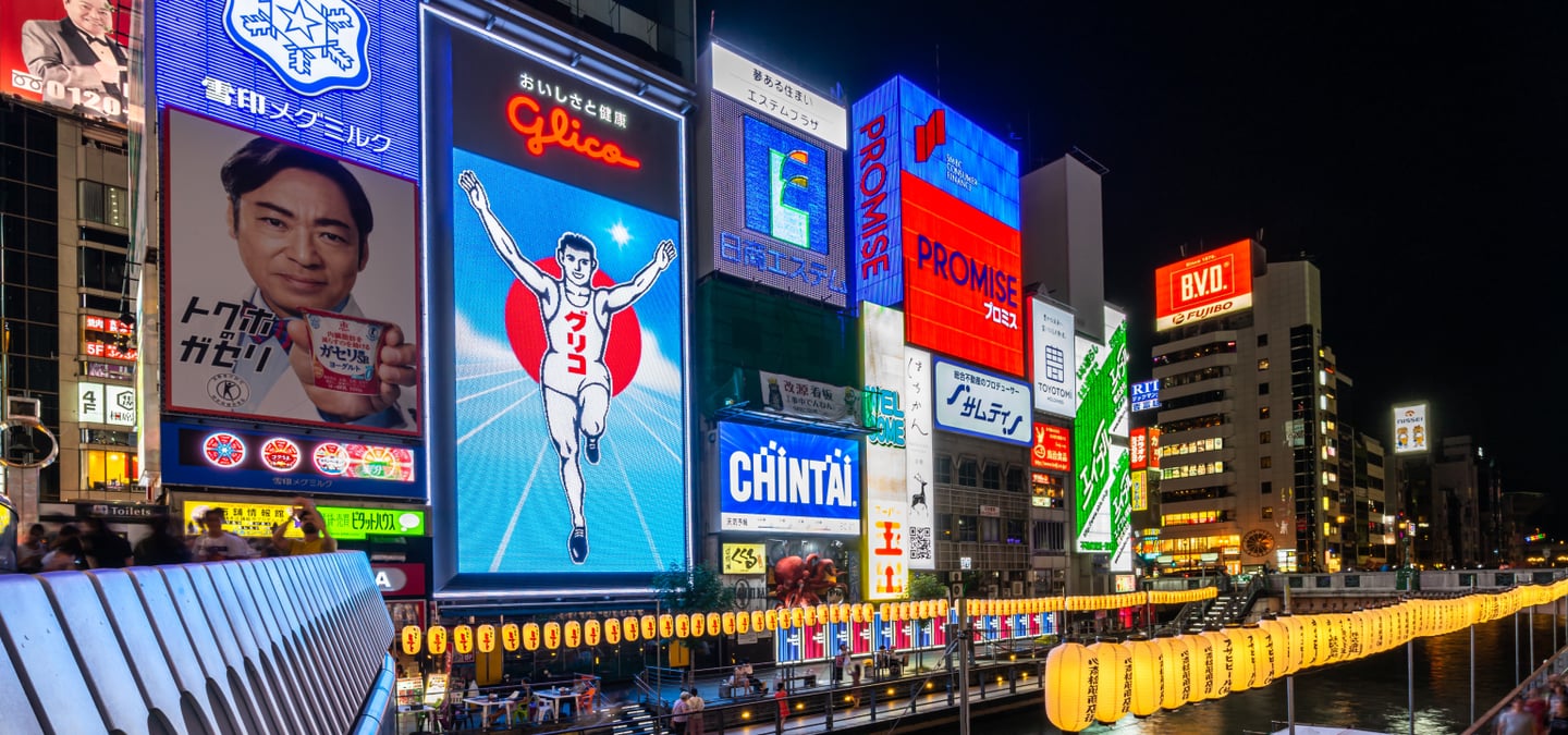 오사카의 상징인 글리코상 전광판과 화려한 네온사인 광고들이 도톤보리 강변 건물을 가득 채운 활기찬 밤 풍경입니다.