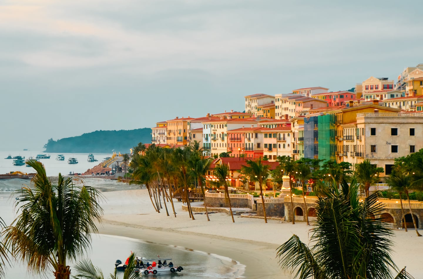 에메랄드빛 바다와 하얀 모래사장 뒤로 파스텔 톤의 화려한 건물들이 조화를 이루는 베트남 푸꾸옥의 아름다운 해변 마을 전경입니다.