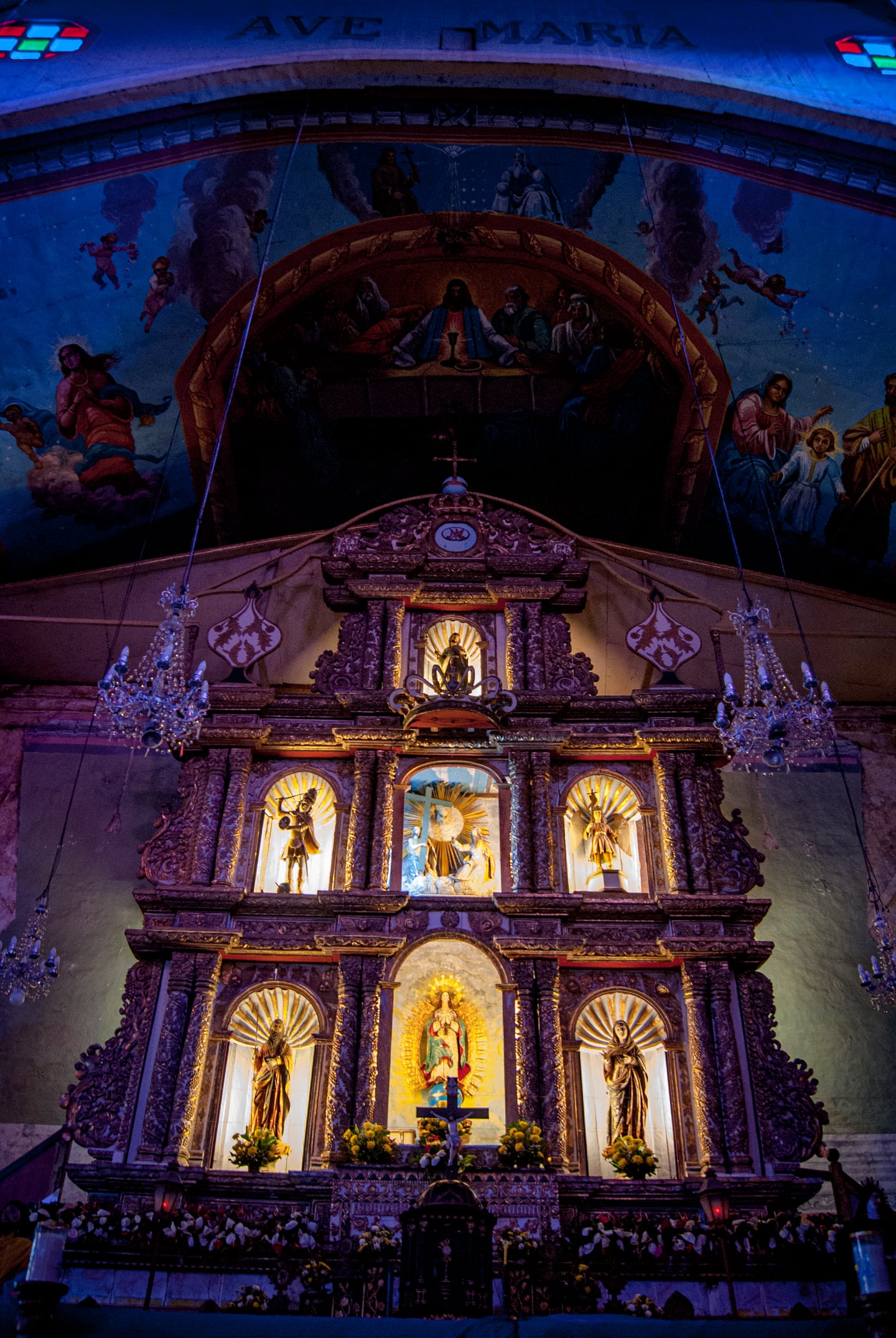 정교한 조각의 황금빛 제단과 푸른색 천장 벽화가 어우러진 성당 내부의 장엄하고 신비로운 분위기를 담은 사진입니다.