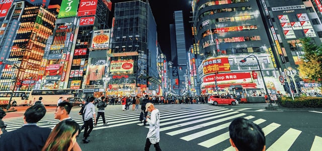 화려한 네온사인과 대형 광고판이 가득한 도쿄 신주쿠 가부키초 거리에서 수많은 보행자들이 횡단보도를 건너는 역동적인 밤 풍경입니다.