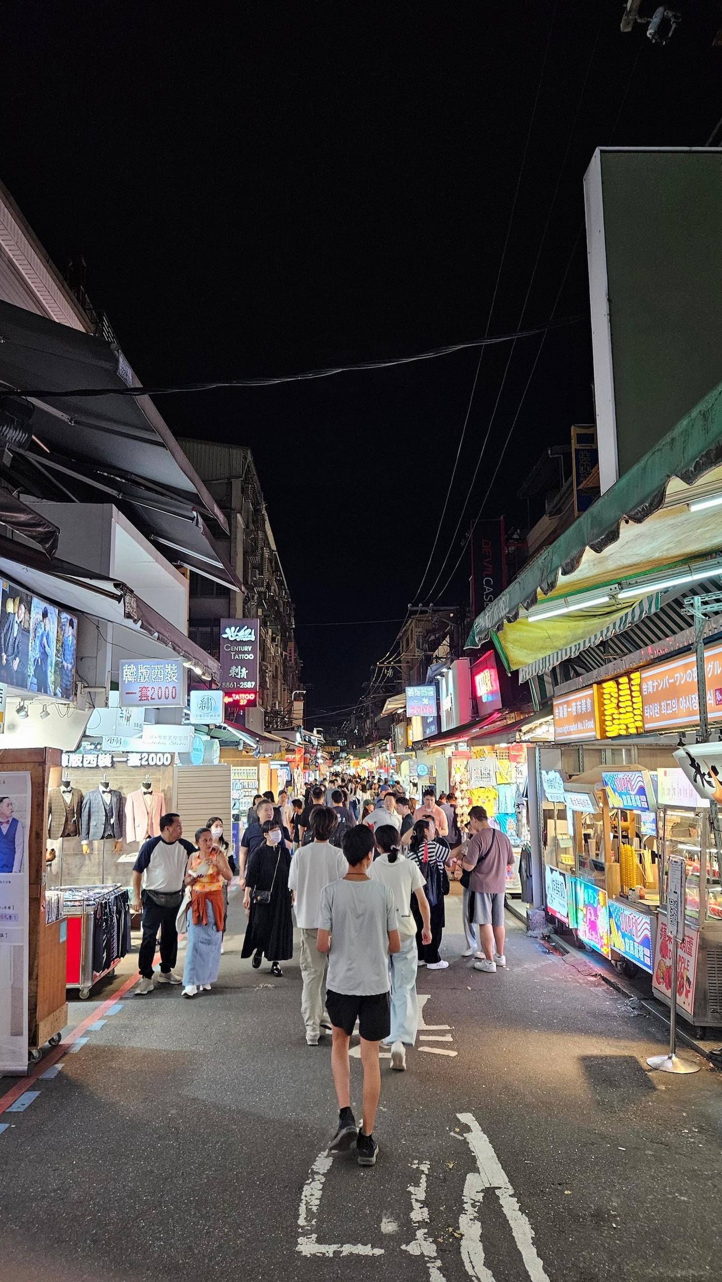 밤늦은 시간까지 인파로 북적이는 대만 야시장의 좁은 골목길을 따라 늘어선 상점들과 노점들의 화려한 조명 풍경입니다.