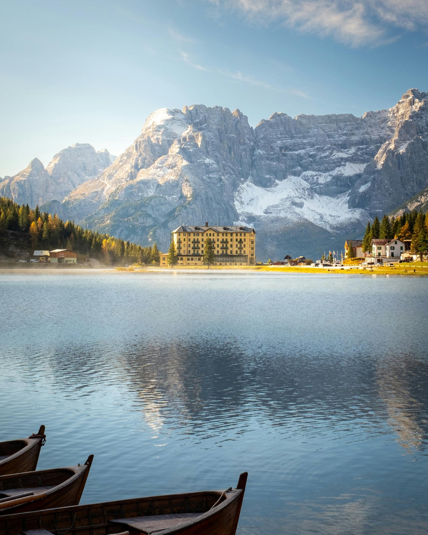 돌로미테 미주리나 호수, 설산으로 둘러싸인 푸른 호수와 고풍스러운 노란색 호텔 건물이 어우러진 평화로운 풍경입니다.