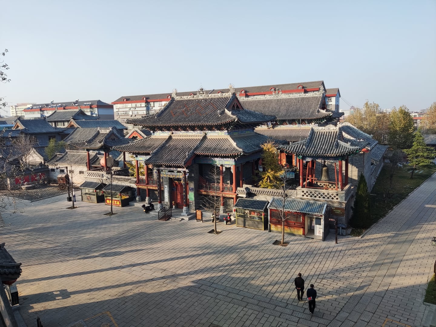 칭다오 청주 고성, 화려한 기와지붕과 붉은 기둥이 조화를 이루는 고대 중국 전통 건축물과 넓은 광장의 전경입니다.