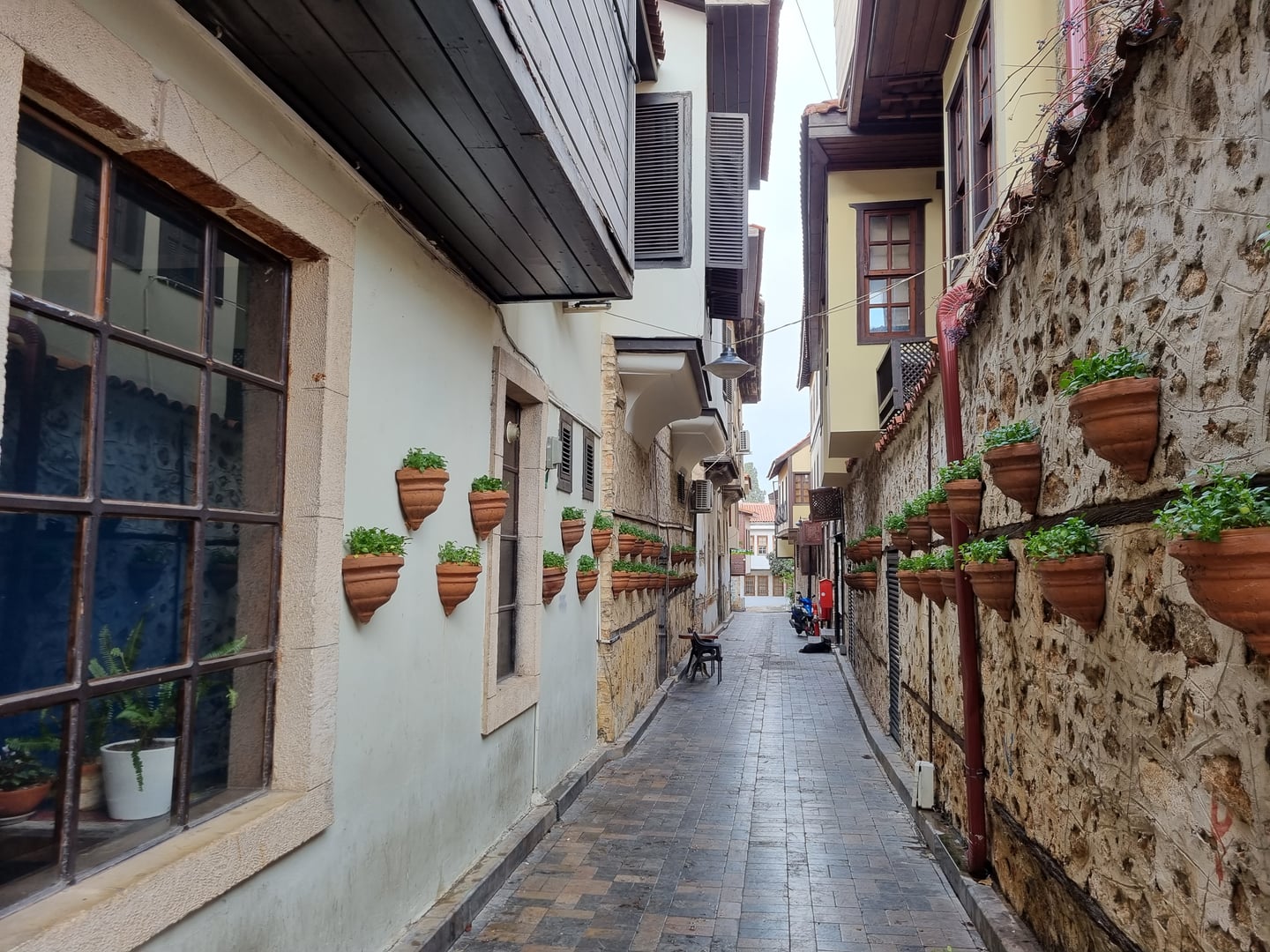 안탈리아 안탈리아 구시가지, 고풍스러운 돌담 벽면을 따라 붉은 토기 화분들이 장식된 좁고 아늑한 칼레이치 골목길의 전경입니다.