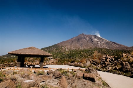 가고시마 센간엔, 전통 가옥의 기와지붕과 정원수 너머로 구름에 싸인 사쿠라지마 화산이 긴코만과 어우러진 풍경입니다.