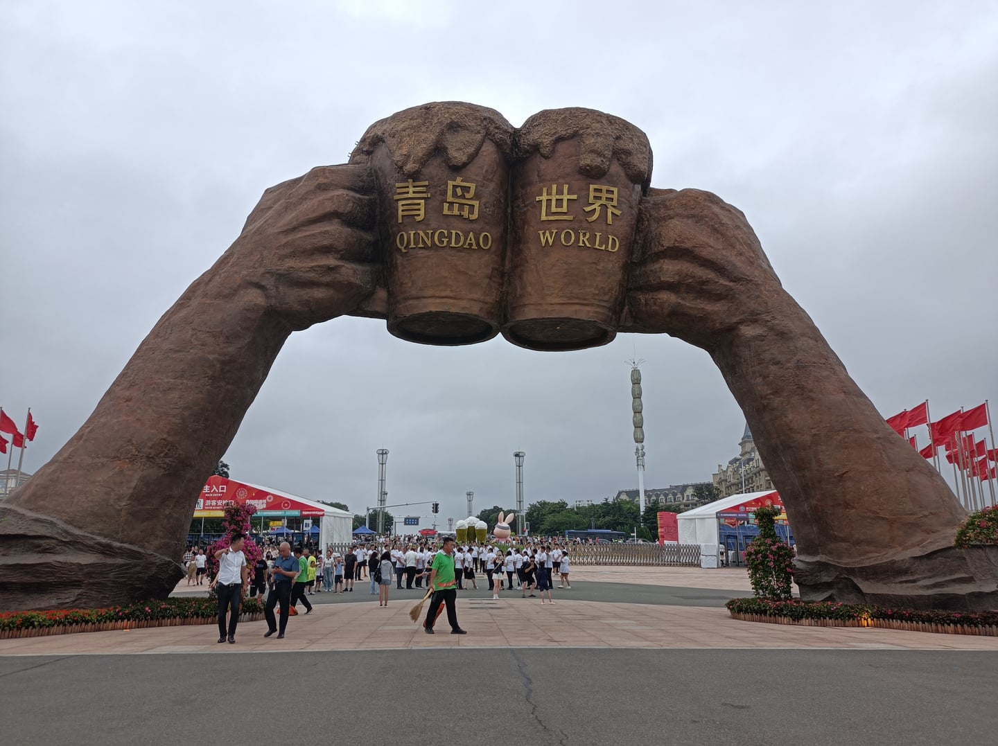 칭다오 국제 맥주 축제, 거대한 맥주잔 조형물이 세워진 축제장 입구에서 많은 사람들이 활기차게 이동하는 풍경입니다.