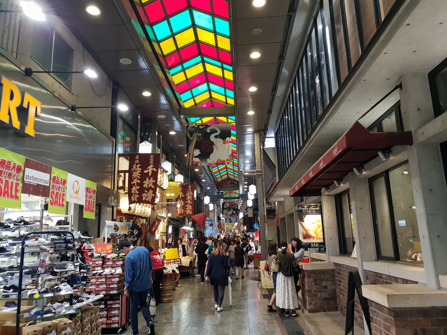 교토 테라마치 거리, 화려한 색상의 천장 아래로 신발 가게와 다양한 상점들이 늘어선 활기찬 아케이드 상점가의 풍경입니다.