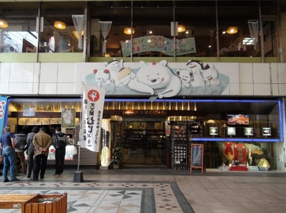 가고시마 텐몬칸, 귀여운 백곰 캐릭터 간판이 돋보이는 유명 빙수 맛집 무쟈키 본점의 활기찬 입구 모습입니다.