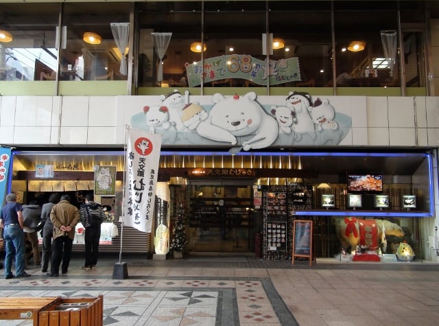 가고시마 텐몬칸, 귀여운 백곰 캐릭터 간판이 돋보이는 유명 빙수 맛집 무쟈키 본점의 활기찬 입구 모습입니다.