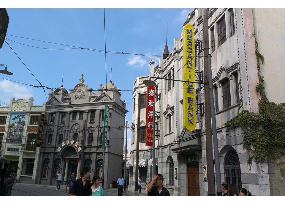 상하이 상하이 영화 촬영소, 1930년대 조계지 스타일의 고전적인 건물들과 화려한 세로형 간판이 늘어선 이국적인 거리 풍경입니다.