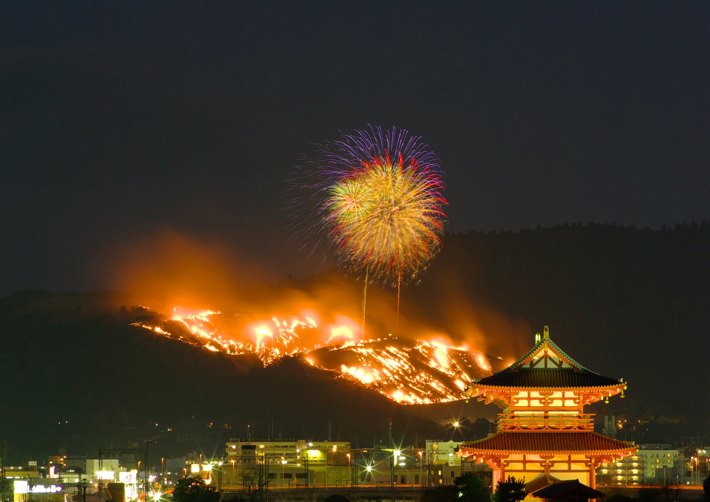 나라 와카쿠사야마, 밤하늘을 수놓는 화려한 불꽃놀이와 산등성이를 따라 타오르는 야마야키 축제의 장엄한 야경입니다.