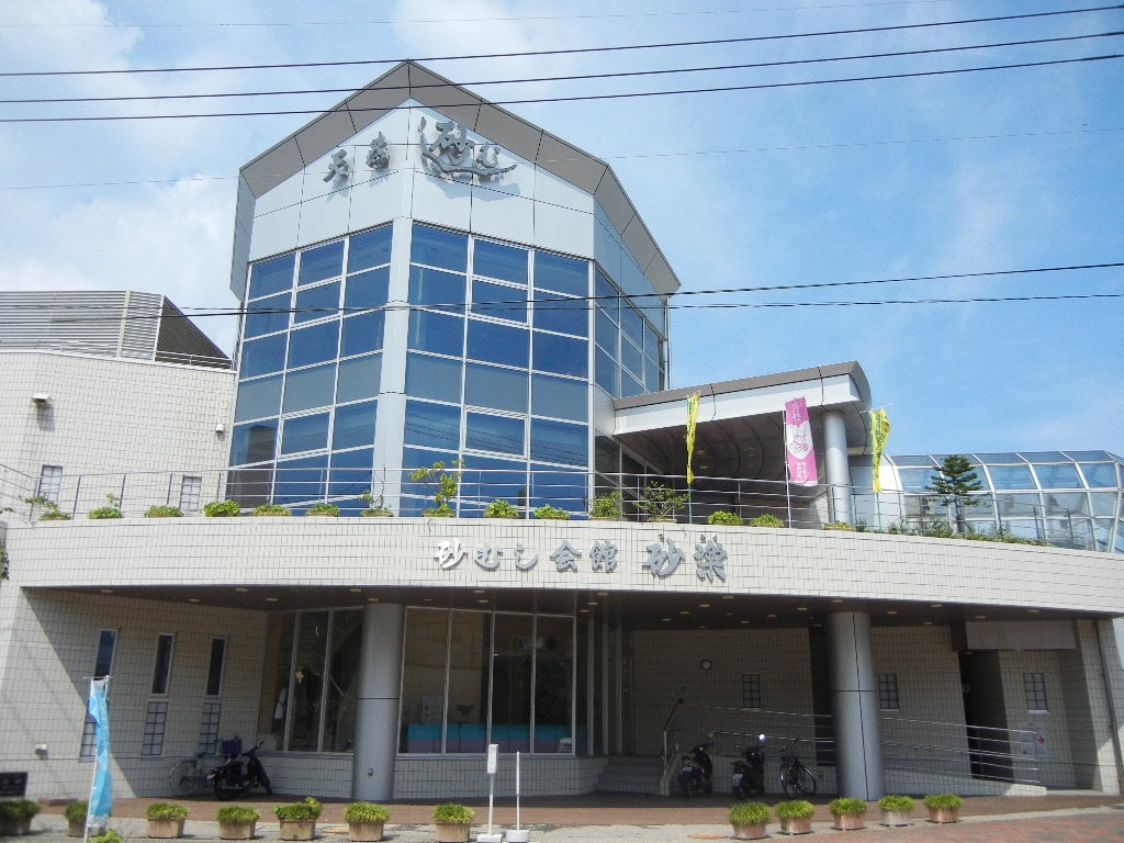 가고시마 이부스키 온천, 푸른 하늘 아래 현대적인 외관을 자랑하는 사라쿠 모래 찜질 회관의 전경입니다.