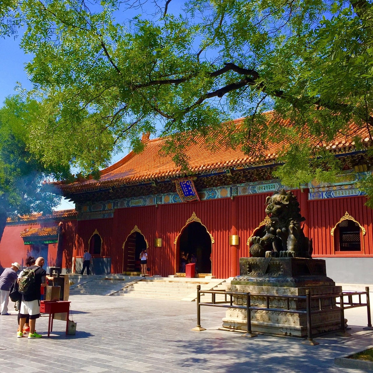 베이징 베이징 라마 사원, 붉은 사원 건물과 해태 석상 그리고 향을 피우는 방문객들이 어우러진 평화로운 풍경입니다.
