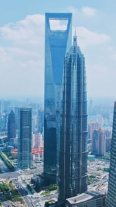 상하이 상하이 세계금융센터, 푸른 하늘 아래 독특한 사다리꼴 상단부와 진마오 타워가 어우러진 웅장한 마천루 전경입니다.