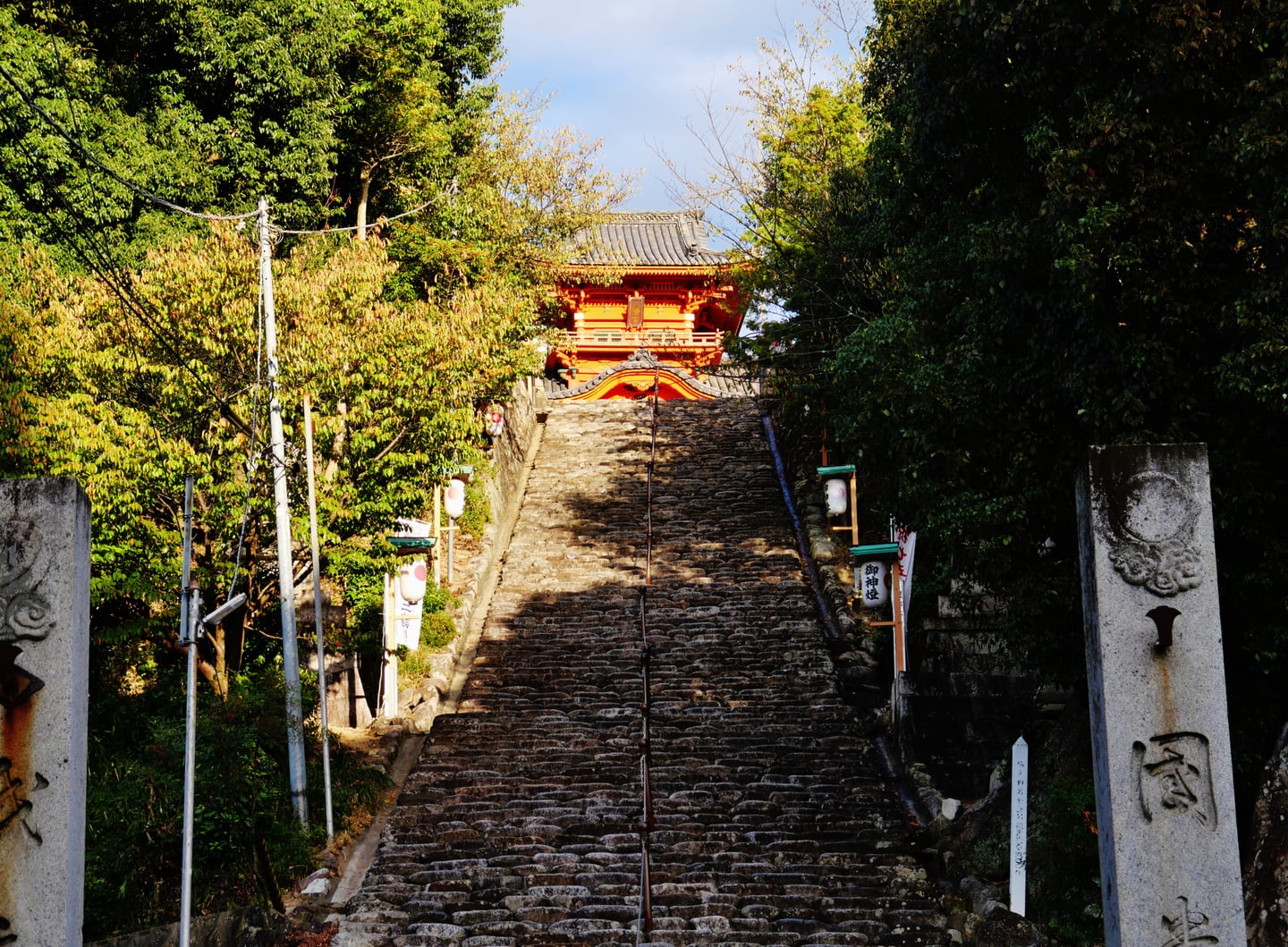 마쓰야마 이사니와 신사, 울창한 숲 사이로 길게 뻗은 가파른 돌계단 끝에 화려한 주황빛 신사 건물이 자리 잡고 있습니다.