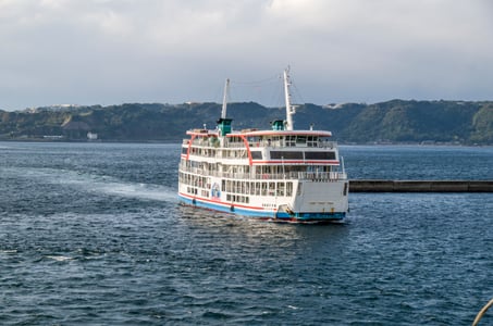 가고시마 사쿠라지마 페리, 푸른 킨코만 바다 위를 가로지르며 항해하는 흰색 대형 여객선의 활기찬 풍경입니다.