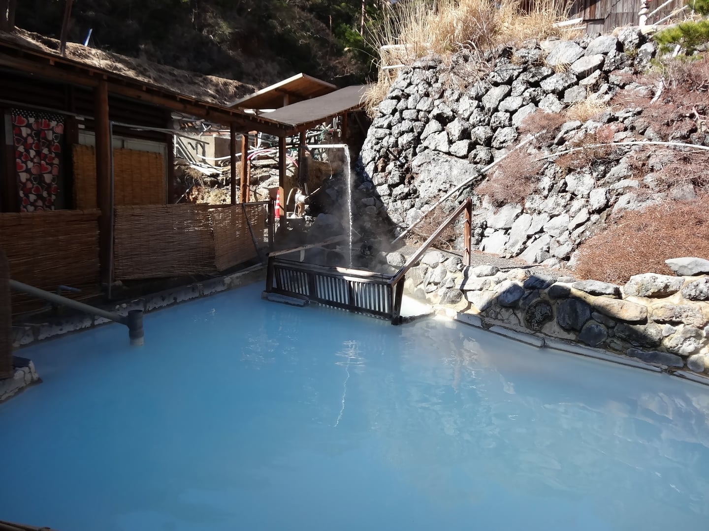 기리시마 기리시마 온천, 푸른빛의 신비로운 온천수가 가득한 노천탕과 고즈넉한 목조 건물이 어우러진 평화로운 풍경입니다.