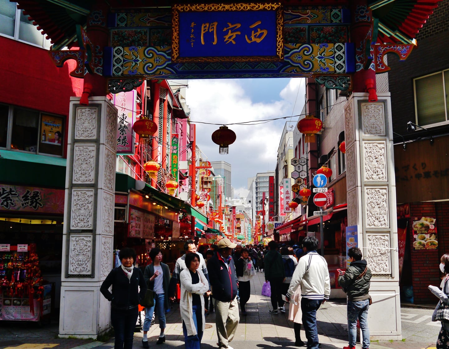 고베 난킨마치, 화려한 장식의 서안문 아래로 활기찬 차이나타운 거리와 인파가 어우러진 풍경입니다.