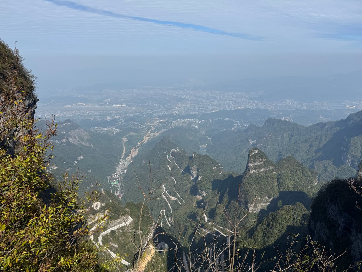 장가계 천문산, 깎아지른 절벽 아래로 굽이굽이 이어지는 통천대도와 구름 너머로 펼쳐진 광활한 도시 전경이 장관을 이룹니다.