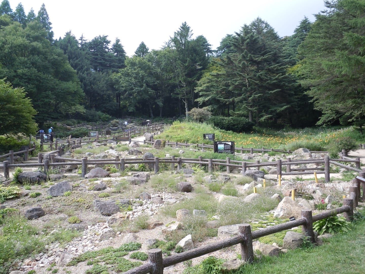 고베 롯코산, 나무 울타리가 둘러진 산책로와 바위 사이로 피어난 고산 식물들이 어우러진 평화로운 정원 풍경입니다.