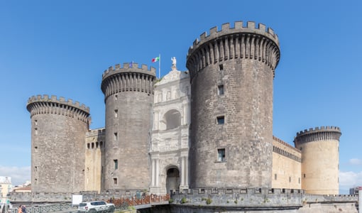 나폴리 누오보 성, 거대한 원통형 타워들 사이에 위치한 화려한 대리석 개선문과 고풍스러운 성벽의 웅장한 모습입니다.